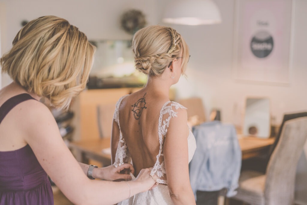 Braut zieht Kleid an beim GettingReady